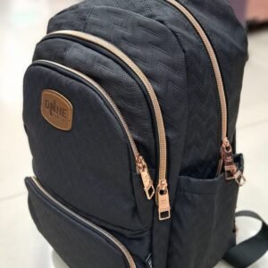 Morral negro de alta gama con patrón de tejido en zigzag, cierres de metal dorado rosa, logotipo DNHE bordado en parche de cuero café y múltiples compartimentos frontales.